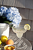 An outdoor table with lemonade with vodka, a sprig of thyme, lemons and peaches
