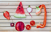 Flatlay of colorful red fruits and vegetables arranged on a wooden background