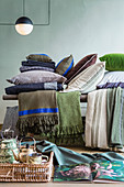 Blanket and cushions in natural shades on bench behind teapot on tray