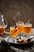 Hot mulled apple juice with spices, cinnamon, cloves, star anise, orange slices and zest