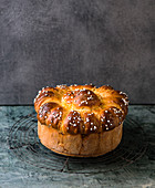 An Easter brioche with sugar nibs on a wire rack against a grey background