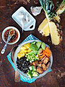 Bowl with black rice, tofu, cucumber, carrot, avocado, pineapple and leek