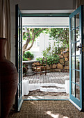 Blick durch geöffnete blaue Flügeltüren in sommerlichen Innenhof