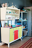 Multicoloured retro dresser next to industrial-style metal shelves