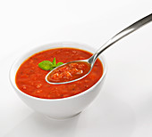 Tomatensuppe mit Speck im Schälchen vor weißem Hintergrund