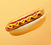 Ein gegrillter Hot Dog mit Senf und Ketchup vor farbigem Hintergrund