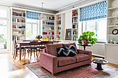 Sofy, dining area and white fitted shelving in open-plan interior