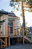 Tiny House aus Holz auf Stelzen mit Treppenaufgang und kleiner Veranda