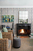 Rattan armchairs in front of open fireplace in living room with grey wallpaper