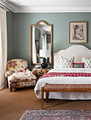 Romantisch elegantes Schlafzimmer mit Bettbank und geblümtem Polstersessel