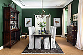 Antique furniture in elegant dining room with green walls