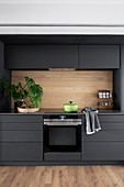 Charcoal-grey kitchen with wall units and wooden splashback