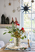 Wintry bouquet with branches and amaryllis on table next to window