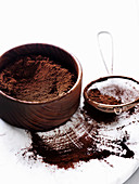 Cocoa powder in wooden bowl and sieve