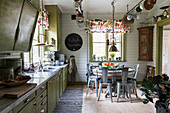 Metal chairs around pedestal table in large kitchen-dining room with retro furnishings