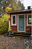 Falu-red Swedish house with blue-grey front door in autumnal garden