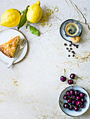 A piece of lemon cake, lemons, espresso and cherries