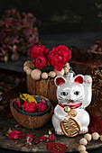 Arrangement of Maneki-neko cat and red roses in coconut shell