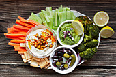 Appetizing healthy hummus green sauce cut carrot cucumbers and green broccoli salted cucumbers decorated with sliced lemon