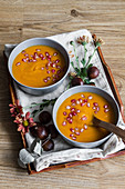 Arrangement with creamy pumpkin soup with chestnut and pomegranate seeds in bowl with spoon