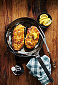 Viennese veal schnitzel in a rustic cast iron pan on a wooden table
