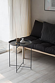 Simple futon sofa with black cushions and side table in corner