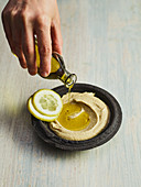 Olive oil being poured onto Israeli hummus