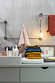 Horizontal and vertical metal rods mounted on wall as towel rail and lamp holder