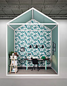 Creative design for study area with desk against wall covered in leaf-patterned wallpaper