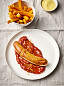 Game sausage with a curry sauce, chips and a dip