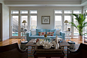 Pale blue sofa in front of large windows in exotic living room