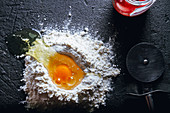 Broken egg in flour with round knife for cutting dough and glass pot