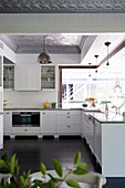 L-shaped kitchen counter with white base units in open-plan kitchen with dark wooden floor