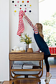 Girl hanging clothing on Eames Hang-It-All coat rack above serving trolley