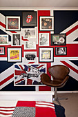 Vintage leather chair next to posters on wall covered with Union-flag wallpaper
