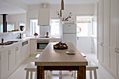 Wooden table with marble top and stools in white kitchen