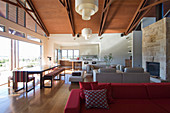 Red sofa, lounge area and dining area next to terrace doors in open-plan interior