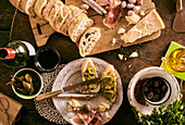 Bruschetta mit Pesto, Minisalami, Oliven, Parmesan, Olivenöl, Riesenkapern und Rotwein