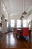 Dining table and kitchen in double-height interior with arched, white wooden ceiling