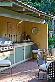 Terrassenbereich im nostalgischen Landhausstil mit überdachter Outdoor-Küchenzeile und Grill