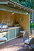 Roofed outdoor kitchen with barbecue on terrace in vintage country-house style