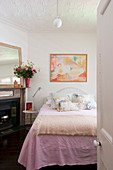 Nude painting above bed with pink bedspread in romantic, feminine bedroom