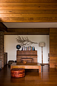 Couchtisch und Klavier in Wohnraum mit Dielenboden und abgehängter Holzdecke