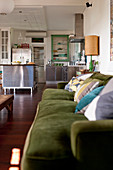 Moss-green sofa and stainless steel kitchen in vintage-style, open-plan interior