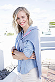 A blonde woman wearing a denim shirt with a jumper over her shoulders