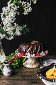 Schokoladen-Kranzkuchen dekoriert mit Obstblüten auf Kuchenständer