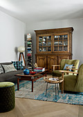 Antique glass-fronted cabinet, vertical book shelf and upholstered seating in living room