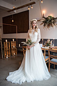 Braut in weißem Brautkleid mit Schleppe im Raum mit Industrie-Flair