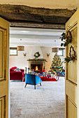 Christmas tree and blue and red furniture in front of open fireplace