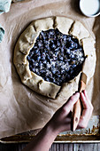 Preparing an autumnal galette with pears and black grapes